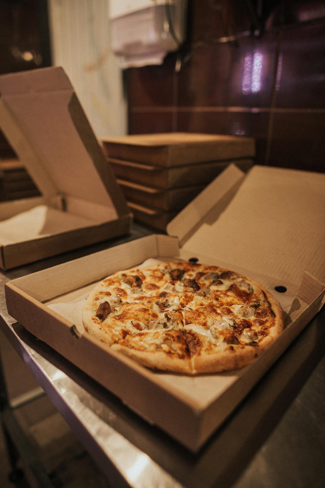 Delicious hot pizza with toppings in an open takeout box on a restaurant table.